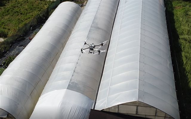 Drone above a polytunnel applying a shading product